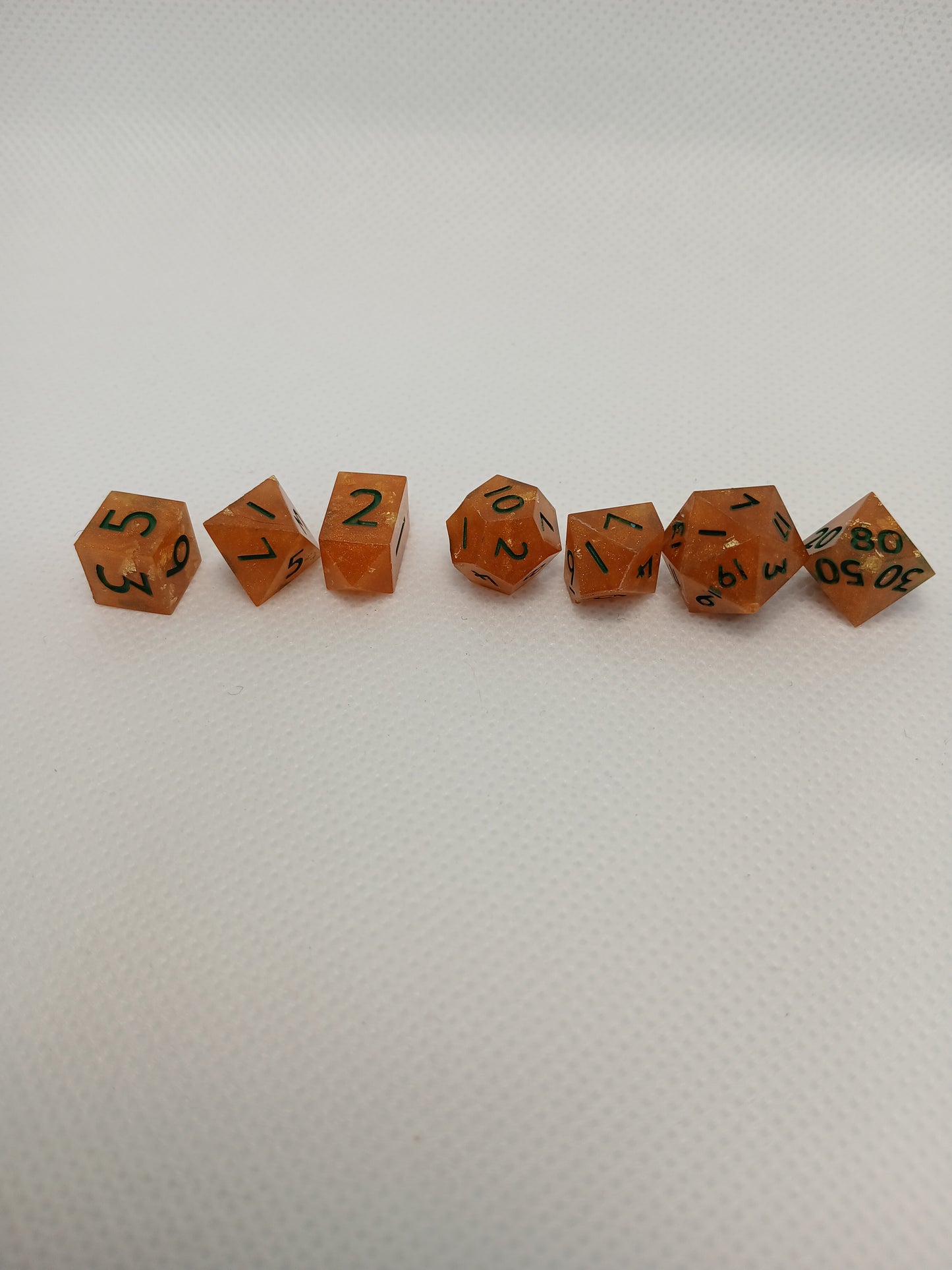 Dice set mini orange med guldglitter och gröna siffror.