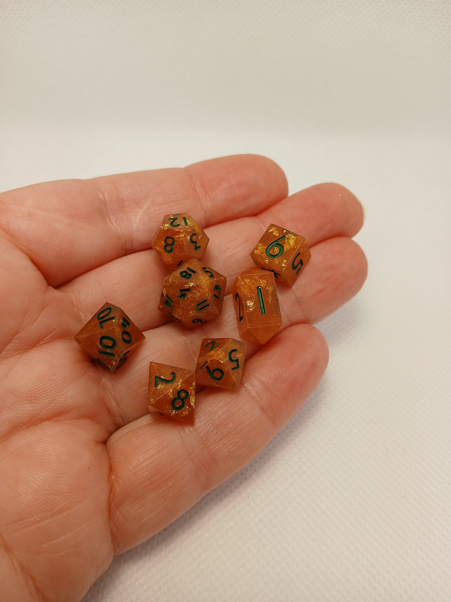Dice set mini orange med guldglitter och gröna siffror.