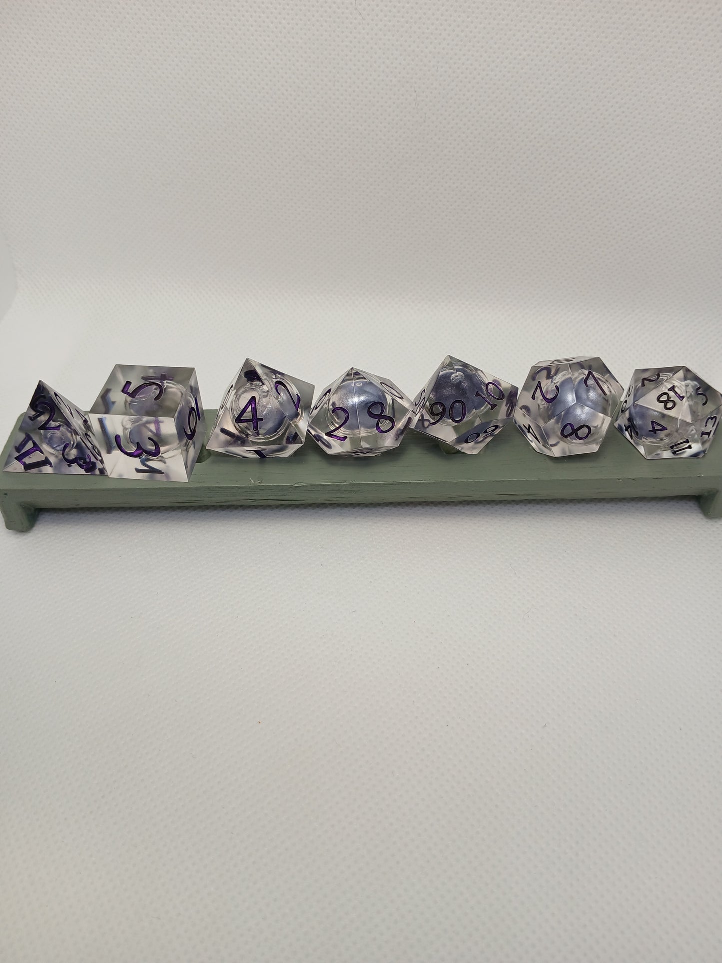 Dice set. Genomskinlig med flytande mitt, lila siffror.
