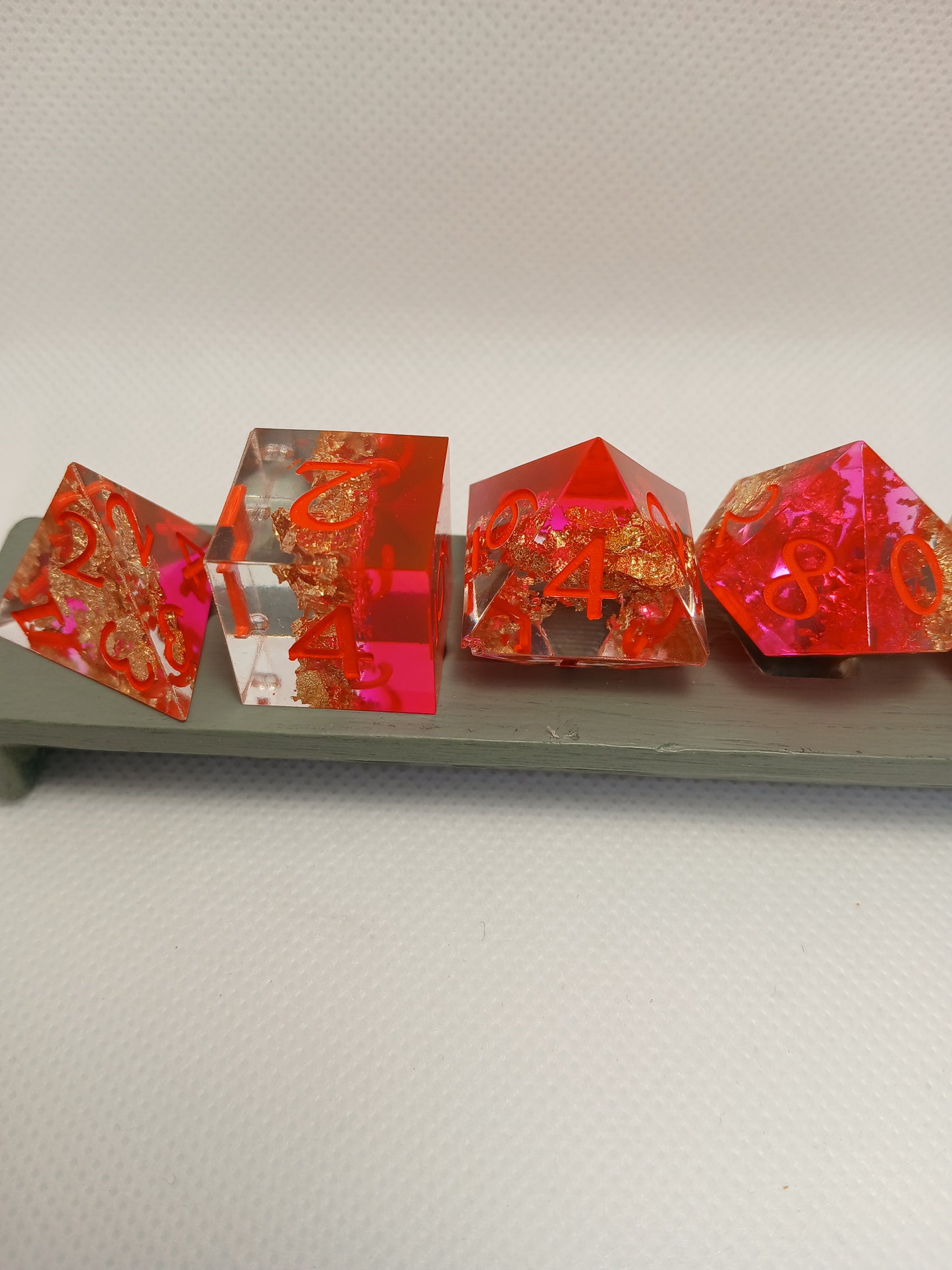 Dice set. Rosa/guldskimmer/genomskinlig med orange siffror.